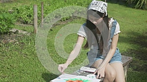 Young asian woman sitting drawing picture with colorful paint brush while leisure in the park on summer.