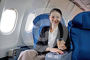 Young Asian woman sitting near the window on a business class airplane during a flight. Travel and business concept.