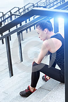 Young asian woman sitting on stadium stairs and looking away