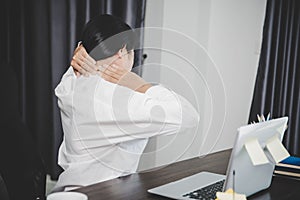 Young asian woman is sitting at work and has tension pain in her neck. Concept office syndrome backache pain from occupational