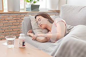 Young Asian woman sleeping and resting on sofa after taking medicines