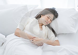 Young Asian woman sleeping in a white bed in the early morning.