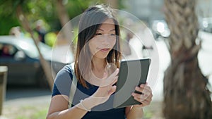 Young asian woman smiling confident using touchpad at street