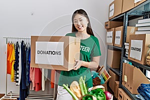 Young asian woman smiling with donated box at donations stand