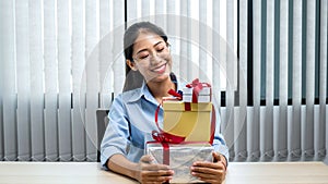 Young asian woman smiling and holding with many gift box at office workspace