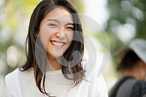 Young Asian woman smiling while looking at camera.