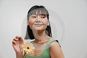 Young asian woman smiling while posing with gerbera flower
