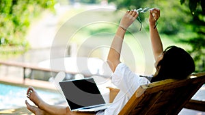 young Asian woman smiling while working on her laptop outside the office, at home, working in the park. work holiday at