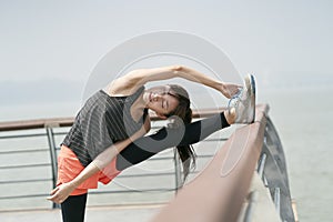 Young asian woman in sportswear stretching body outdoors