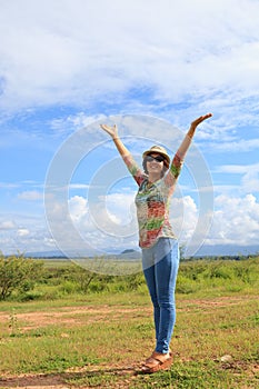 Young asian woman standing in field and rising up her hand with nice emotion