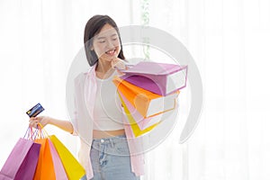 Young asian woman standing holding credit card and paper bag with satisfied.