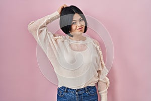 Young asian woman standing over pink background confuse and wonder about question