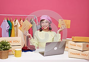 Young asian woman startup small business freelance sale fashion clothing with parcel box and computer laptop on table and sitting