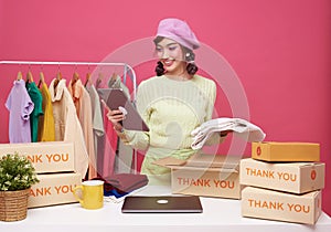 Young asian woman startup small business freelance sale fashion clothing with parcel box and computer laptop on table and sitting