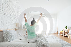 Young Asian woman stretching on bed after wake up