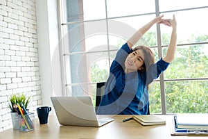 Young asian woman stretching body for relaxing while working with laptop computer at her desk, home office lifestyle, business