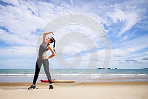 Young Asian woman is stretching or warm-up her body before exercise by running on the beach in the morning and get fresh air.