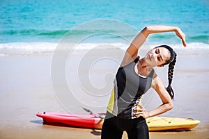 Young Asian woman is stretching or warm-up her body before exercise by running on the beach in the morning and get fresh air.