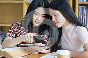 Young Asian woman student study and take notes with book in library. F