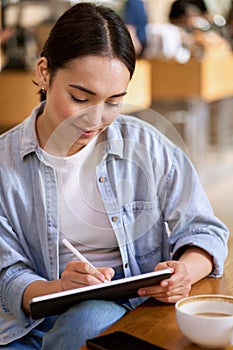 Young Asian woman student using digital tablet for elearning.