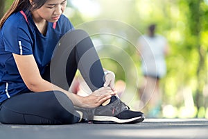 Young asian woman suffering ankle injury. Runner girl is injured by sprain ankle while running or exercising. Female runner