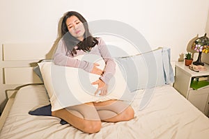 Young Asian woman suffering menses abdominal cramp - sick and tired Japanese girl lying on bed having having period pain holding photo