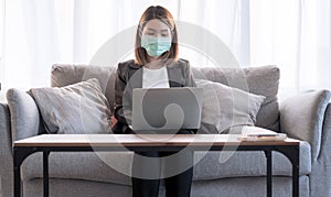 Young Asian woman in a suit is sitting and working at her house.