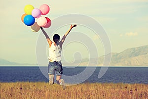 Young asian woman on sunset grassland with colored balloons