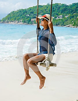 Young Asian women at a swing on a tropical beach in Mahe Tropical Seychelles Islands