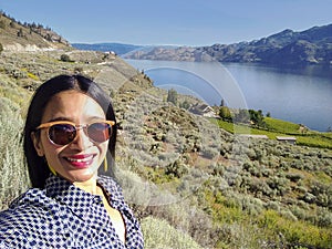 Young Asian woman taking selfie at Okanagan lake Canada