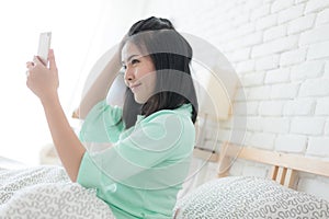 Young Asian woman taking selfie photo in bedroom