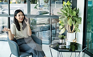 Young Asian woman talking on the mobile phone working on smartphone In modern office