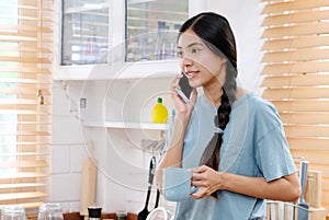 Young asian woman talking phone in kitchen background, people lifestyle