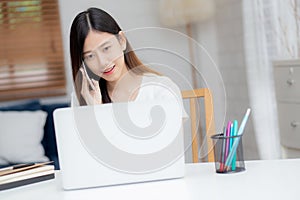 Young asian woman talking phone and work from home with laptop computer.