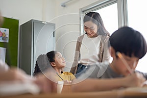 Young Asian Woman Teacher teaching her African American girl in classroom