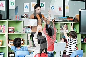 Young asian woman teacher teaching kids in kindergarten classroom, preschool education concept