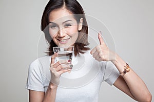 Young Asian woman thumbs up with a glass of drinking water.