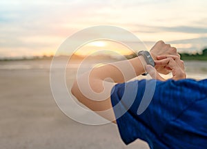 Young Asian woman touching smart band after running in the morning. Wearable computer. Heart rate monitor bracelet. Fitness device