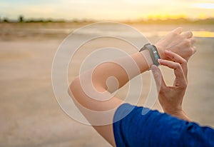 Young Asian woman touching smart band after running in the morning. Wearable computer. Heart rate monitor bracelet. Fitness device