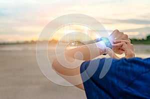 Young Asian woman touching smart band after running in the morning. Wearable computer. Heart rate monitor bracelet. Fitness device