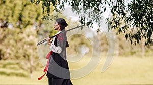 Young asian woman in traditional kimono portrait with katana sword samurai warrior girl in green summer garden