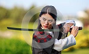 Young asian woman in traditional kimono trains in a fighting stance close-up portrait with katana sword samurai warrior girl in