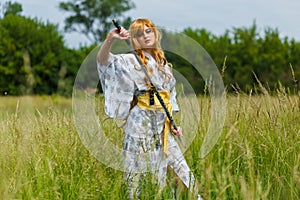 Young asian woman in traditional kimono trains fighting techniques with katana sword
