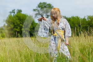 Young asian woman in traditional kimono trains fighting techniques with katana sword