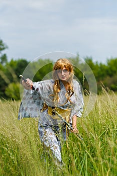 Young asian woman in traditional kimono trains fighting techniques with katana sword