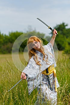 Young asian woman in traditional kimono trains fighting techniques with katana sword