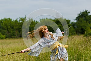 Young asian woman in traditional kimono trains fighting techniques with katana sword