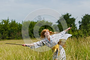 Young asian woman in traditional kimono trains fighting techniques with katana sword