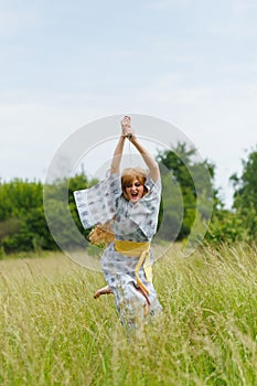 Young asian woman in traditional kimono trains fighting techniques with katana sword