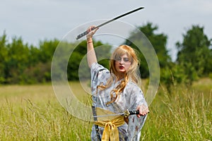 Young asian woman in traditional kimono trains fighting techniques with katana sword